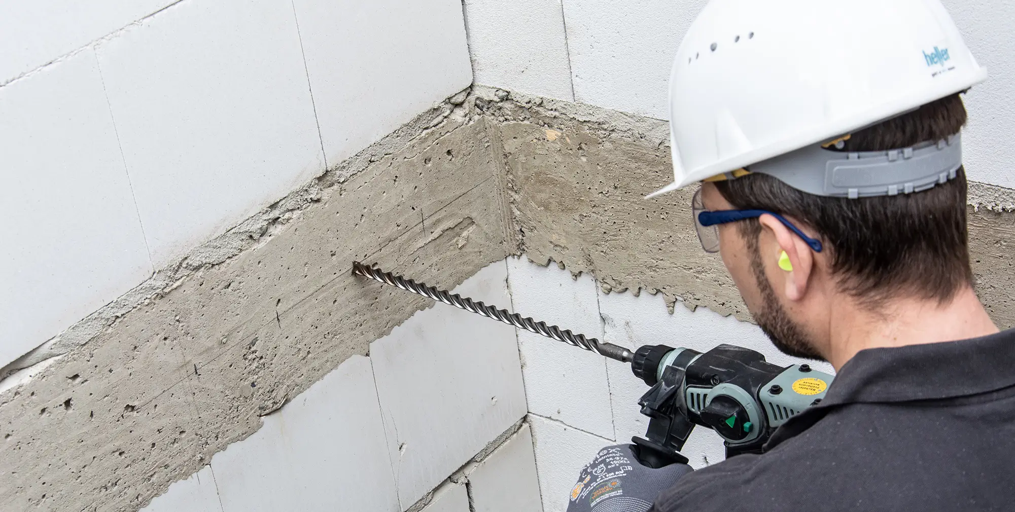 Mann bohrt mit einem SDS-Bohrer in eine Betonwand